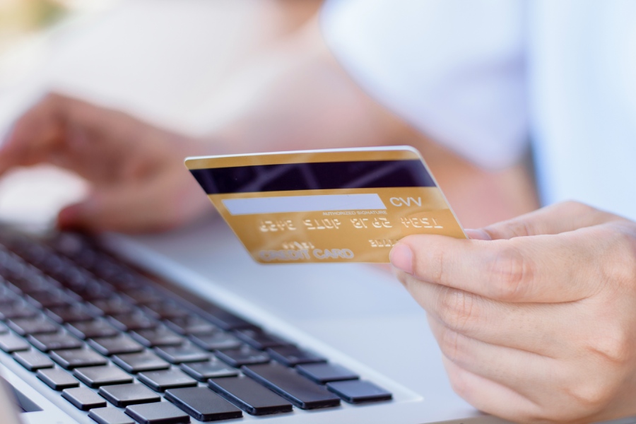 Una mano sostiene una tarjeta mientras realiza una compra online